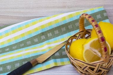 Bir sepet ve bıçak, ahşap zemin ve kumaş üzerine izole taze sulu limon.
