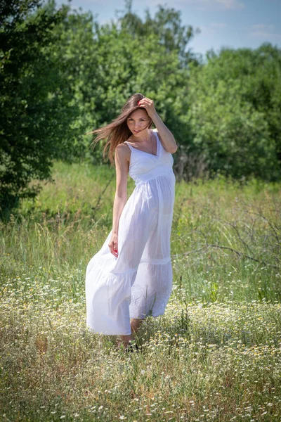 穿着白衣的年轻女子走在夏日的森林小径上 — 图库照片