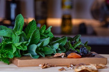 Mutfaktaki yemekler nane, kurutulmuş kayısı, kuru erik ve ahşap kesme tahtasındaki cevizlerle dolu.