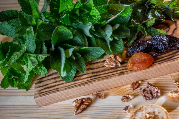 Mutfaktaki yemekler nane, kurutulmuş kayısı, kuru erik ve ahşap kesme tahtasındaki cevizlerle dolu.