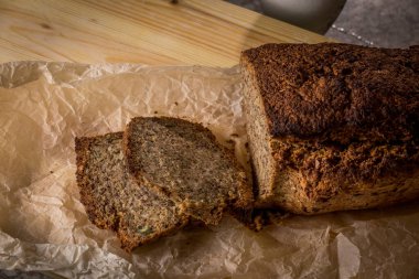 Mutfakta çok tahıllı ev yapımı taze ekmek kesim tahtası ve pergament kağıt.