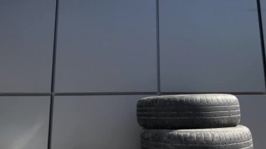 Birbirinin üstüne yığılmış iki kullanılmış lastik kulesi geri dönüşüm ve geri dönüşüm için bekliyor. Güneş üstlerinde parlıyor.