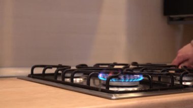 El gazı tutuşturur ocağın üzerindeki ocağı, mavi ateş güçlü bir şekilde yanmaya başlar. Kız ocağın kapağına parlak metal bir tava koyar ve gaz olasılığını azaltır.