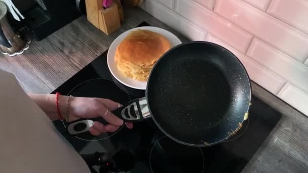 女人们把煎锅从炉子上举起来 把烤好的煎饼扔到厨房里的一堆煎饼上 把面糊倒进勺子里烤一个新的煎饼 — 图库视频影像
