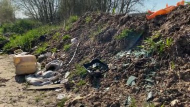 Doğadaki eski çöpler. Fıçı yere düştü. Kırık camlar güneşte parlıyor, eski plastik bir kutu, şişeler, tek kullanımlık sofra takımı, kahve fincanı, maske, çocuk oyuncağı, çantalar, paçavralar. Güneş, bahar çayırı