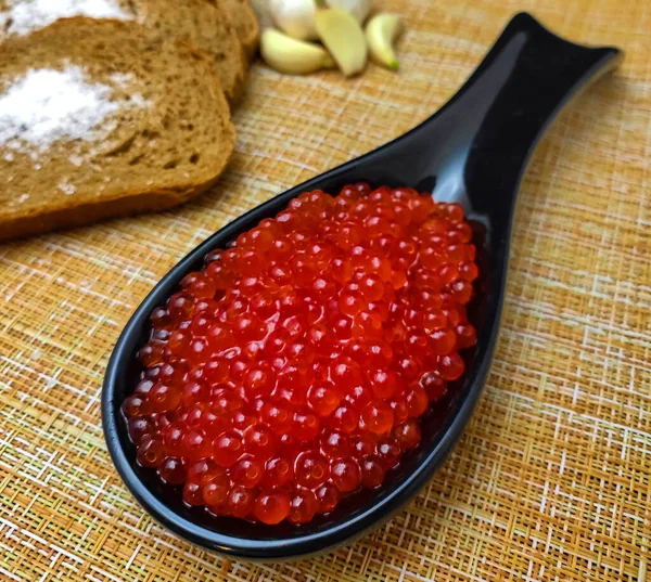 Kırmızı havyar. Denizin lezzeti. Bir kaşıkta, ekmek, tuz ve sarımsak ile. Yukarıdan görünüşü