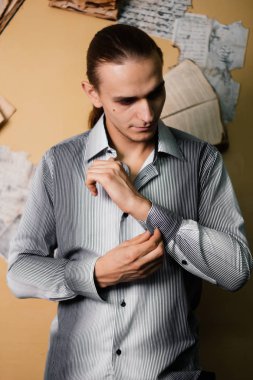 Kitapların arka plan üzerinde çizgili gömlekli yakışıklı adam. Moda fotoğraf. Temiz Cilt ile model. Stüdyo portre. bir düğme ile takılır.