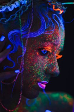 Neon kız portresi. Parlak yüzünde sıçramalarına. Koyu mavi neon lensler ile model. Cadılar Bayramı için görüntü.