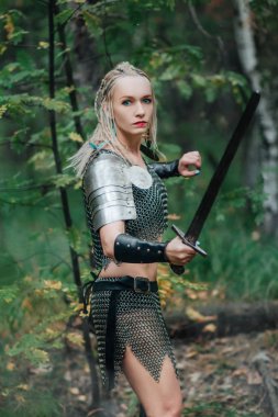 Bir güzel savaşçı kız kılıç ve zırh. Bir zincir etek ve yelek gizemli bir ormandaki modelinde. Fantezi fotoğraf.