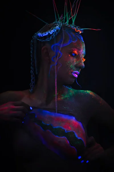 Neon portrait of a girl. Bright splashes on the face. Model with blue neon lenses in the dark. The image for halloween.