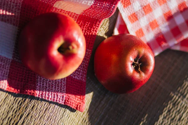 Red juicy apples on a picnic. Towel in a cage. Fruit on straw mat