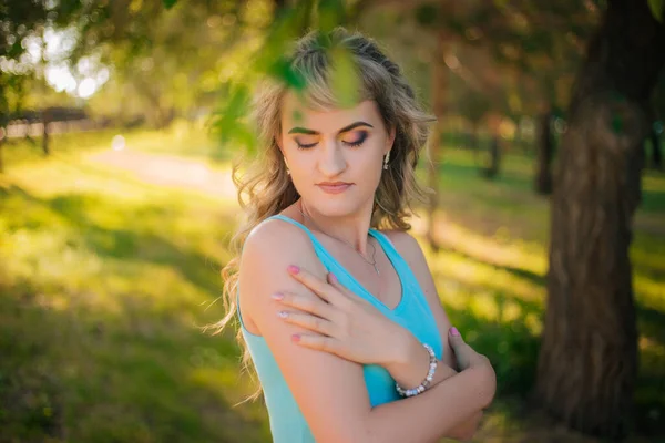 Beautiful girl on a walk in the park. Blonde in a blue t-shirt in the forest. Model with a cheerful smile — 스톡 사진