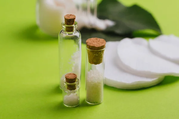 Eco cosmetics. A jar of white cream and the leaves of the tree on a green background. Skin care. Sea salt jars