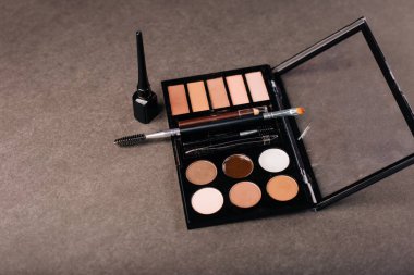 Gri arka planda göz farı paleti. Kaş, göz kapağı makyajı ve boya.