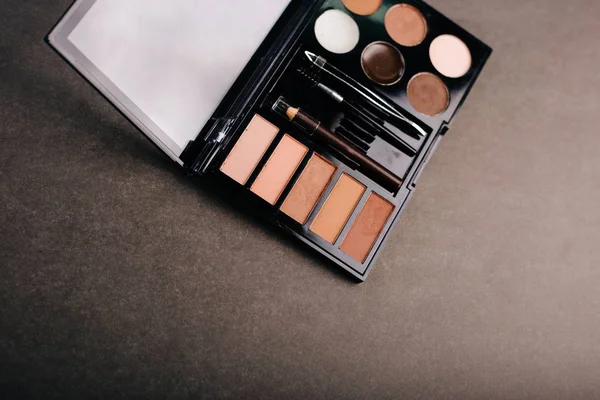 Gri arka planda göz farı paleti. Kaş, göz kapağı makyajı ve boya.