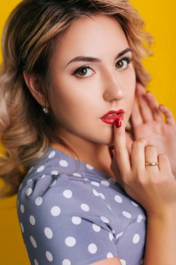 Kırmızı dudaklı bir kız ve sarı arka planda bezelye desenli bir elbise. Pin-up portreleri