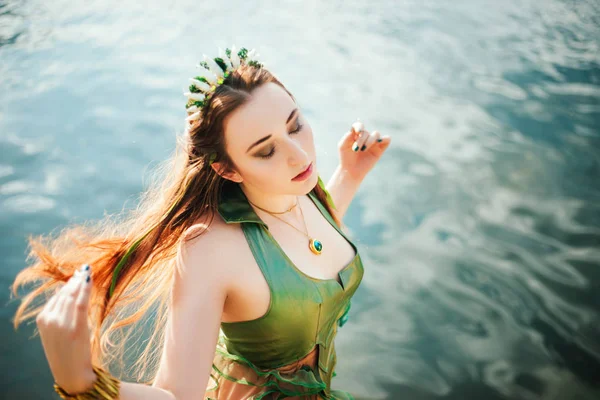 髪に海苔を巻いて緑のドレスを着た女の子が池の近くに立っている シェル付きリム付きモデル — ストック写真