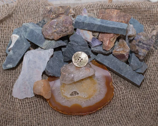 El yapımı metal düğme, arka planda Ural taşları kullanılır.