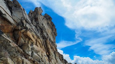 Arka planda büyük kaya ve gökyüzü.