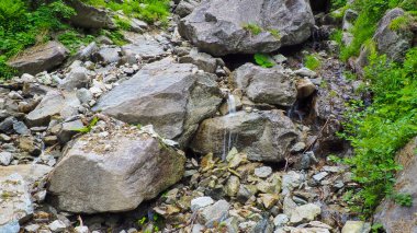 Su yavaşça kayaların üzerinden akıyor..