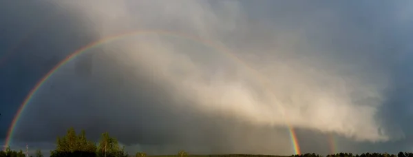 Rainbow over forest Panoramic view Cloudy landscape