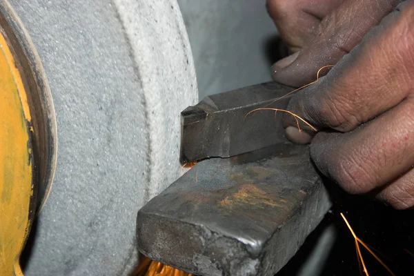 Sharpening a turning tool. Worker\'s hands are grinding a turning tool on an emery machine