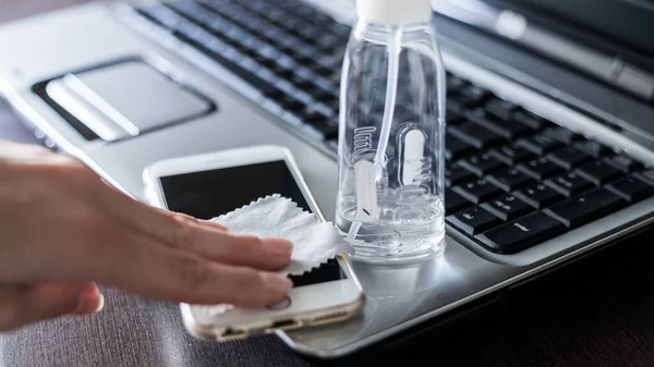 Using a medical protective antibacterial antiseptic gel in the workplace while working online at home at the computer and cleaning mobile phone. Protection at coronavirus and covid