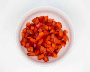 Beyaz arka planda beyaz bir porselen kasede doğranmış taze kırmızı biber.