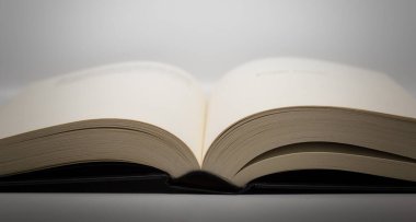 Açık, siyah kapaklı, beyaz arka planda sarı sayfaları olan kalın bir kitap..