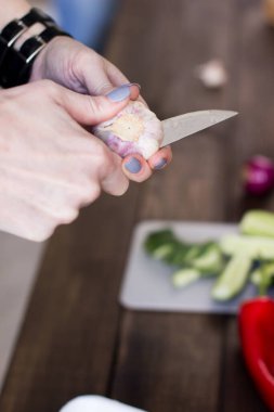 Genç bir kadın sağlıklı sebzeleri dilimliyor.