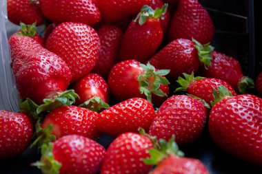 Bir sürü taze, ıslak çilek siyah bir masaya saçılmış.