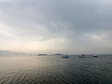 Ufuktaki teknelerin siluetleri denizin yüzeyinde şafakta huzur içinde.