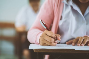 Sınav sorularını yazan ve okuyan öğrenciler, okuldaki sınav kağıtlarını stres ile okuyorlar..