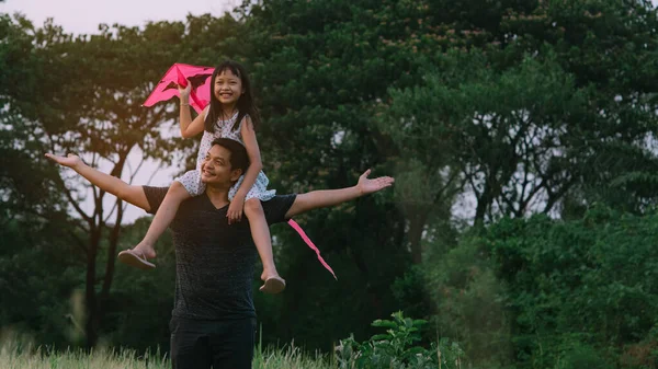 Asyalı Küçük Kız Uçurtmayı Tutarak Yeşil Arka Planda Babasının Omuzlarına — Stok fotoğraf