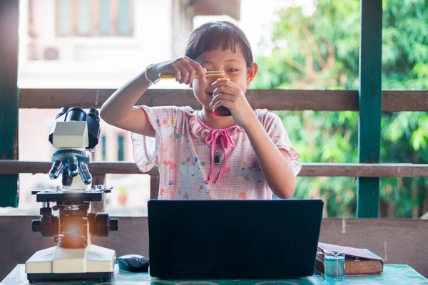 Gülümse küçük kız öğreniyor ve bilimsel deneyler yapıyor. Evde Okul Eğitimi kavramı.