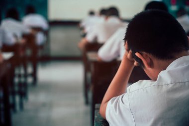 Sınav sorularına cevap veren öğrenciler okul sınıfında stres altında çarşaf egzersizleri yapıyorlar..