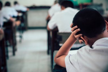 Sınav sorularına cevap veren öğrenciler okul sınıfında stres altında çarşaf egzersizleri yapıyorlar..