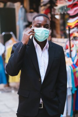 Corona virüsünden veya covid-19 'dan korunmak için tıbbi maskeli Afrikalı işadamı