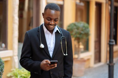 Afrikalı doktorun gülümseyen ve akıllı telefon kullanan portresi