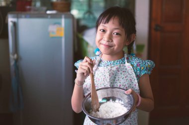 Küçük çocuk önlük giyer ve mutfakta yemek yapmayı öğrenir.