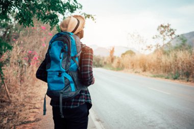 Sırt çantası taşıyan Afrikalı bir gezgin otobanda yürüyor