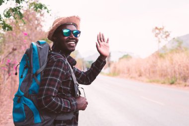 Sırt çantası taşıyan Afrikalı bir gezgin otobanda yürüyor