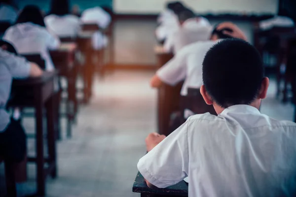 Sınav sorularına cevap veren öğrenciler okul sınıfında stres altında çarşaf egzersizleri yapıyorlar..