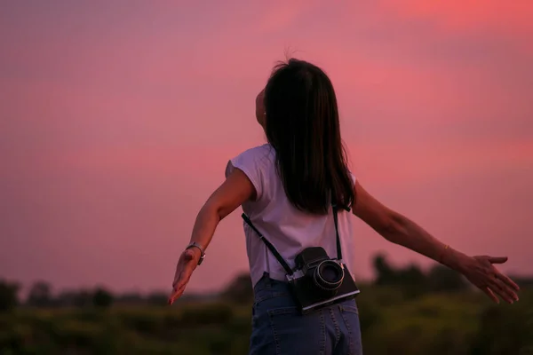 カラフルな夕日の空の背景と中判フィルムカメラを保持している美しい自由アジアの女性の肖像画 — ストック写真