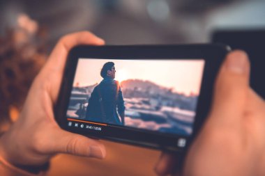 Akıllı telefonlu çevrimiçi film yayını. Cep telefonundan hayali video oynatıcı servisi ile film izleyen kadın.