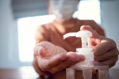 Corona virüs koruması, ellerini dezenfektan jeliyle temizleme, koronavirüs yüzünden karantinada olan koruyucu maske takan bir kadın,.