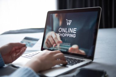 E-ticaret ve çevrimiçi alışveriş kavramı, dizüstü bilgisayar kullanan kadın eli (Mockup web sitesi) ve evde çevrimiçi alışveriş için kredi kartı bulunduruyor.