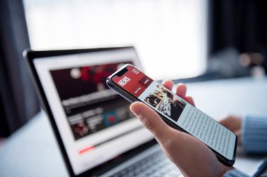 Akıllı telefon ve dizüstü bilgisayardan online haberler. Model web sitesi. Evde cep telefonu ekran uygulamasında haber ya da makale okuyan bir kadın. Gazete ve internet portalı.