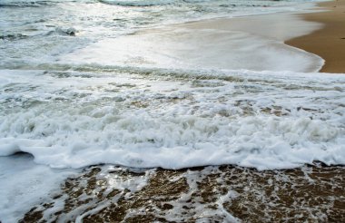 Güneş ışığı bulutların arasından denize akıyor. Somnath tapınağı Gujarat Hindistan 'ın plajından görünüyor.