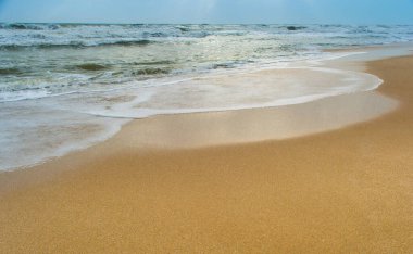 Güneş ışığı bulutların arasından denize akıyor. Somnath tapınağı Gujarat Hindistan 'ın plajından görünüyor.